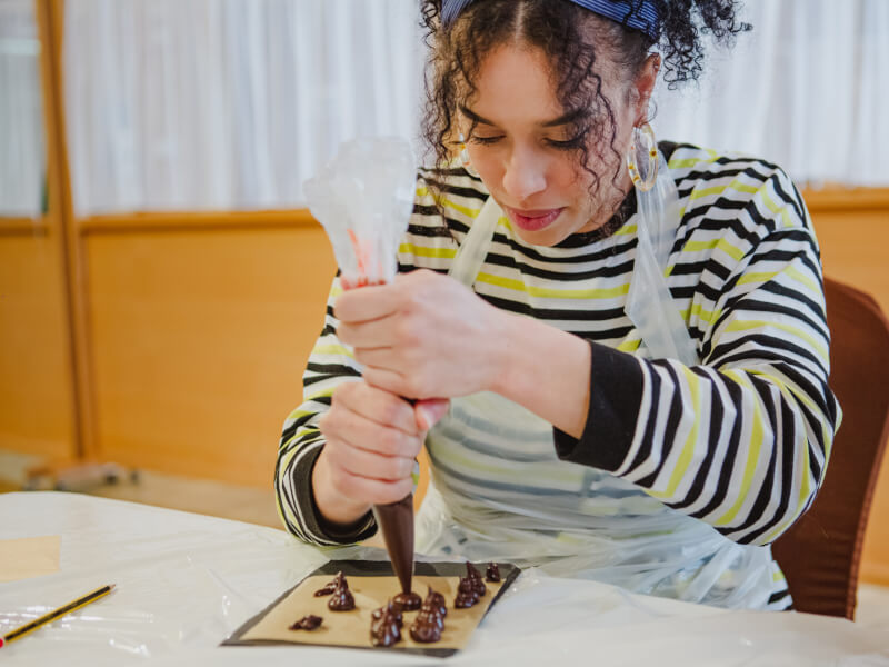 A woman squeezing a piping bag at a chocolate making class.