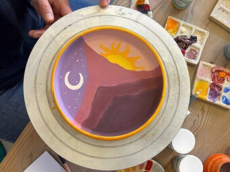 A ceramic plate with a sun and moon painted on