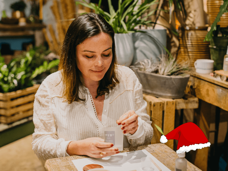 A woman smiles as she looks down at an empty candle jar, ready to fill with eco friendly soy wax