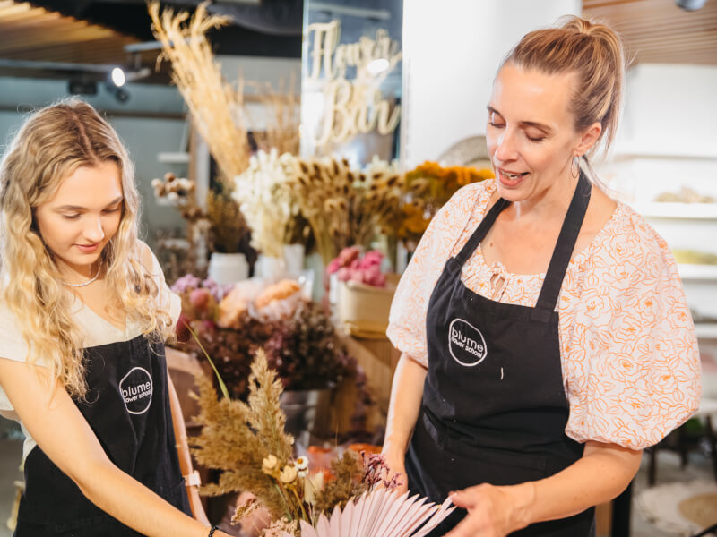 A teacher instructing a student at a floristry class.