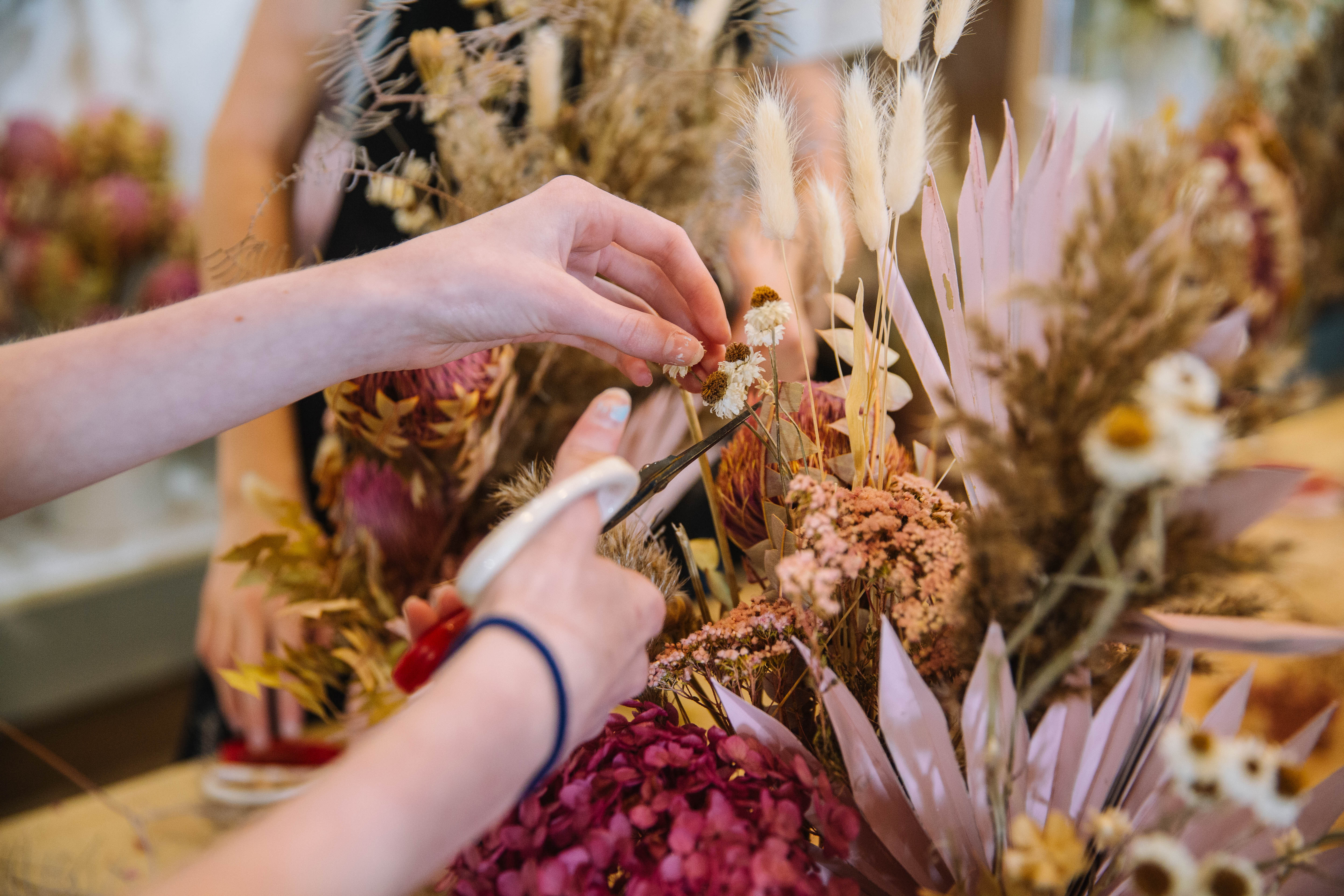 Close up of hands trimming a dried flower bouquet with scissors