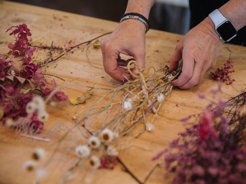 A closeup of a person flower arranging dried stems.
