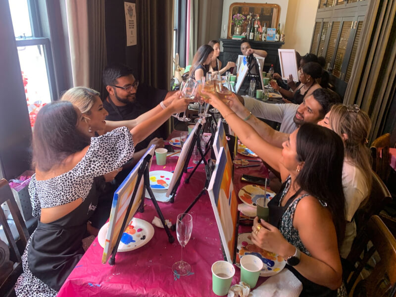 A group of people clinking glasses at a paint and sip night with Paintvine UK