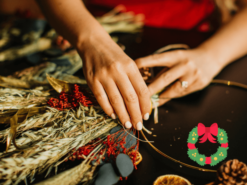 A woman's hands holding warmly coloured dried wreath making materials