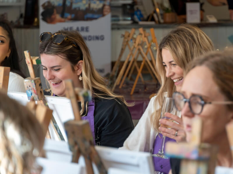 Two women smiling at a paint and sip class