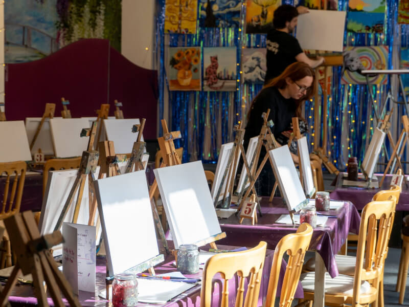 A hall set up with easels for a paint and sip event