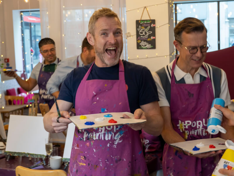 A man holding a paint palette at a paint and sip