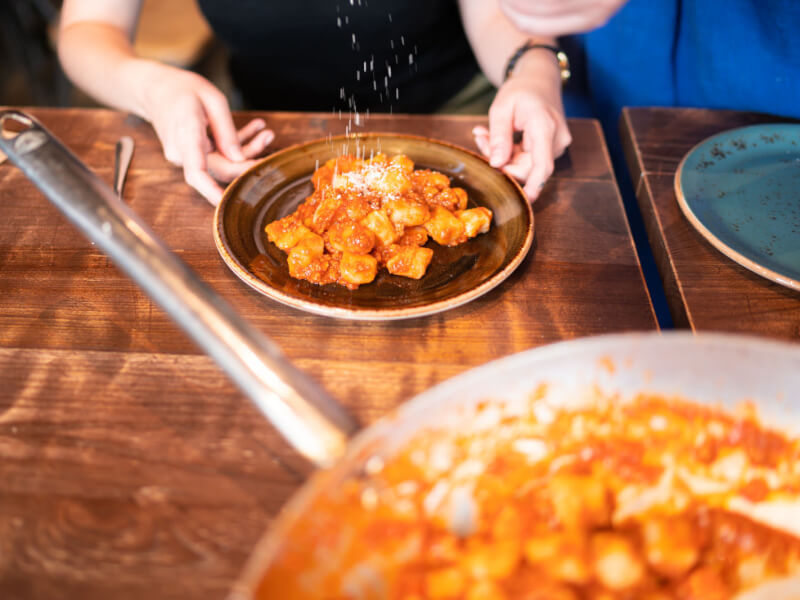 Close up of a person plating up some gnocchi from a pan