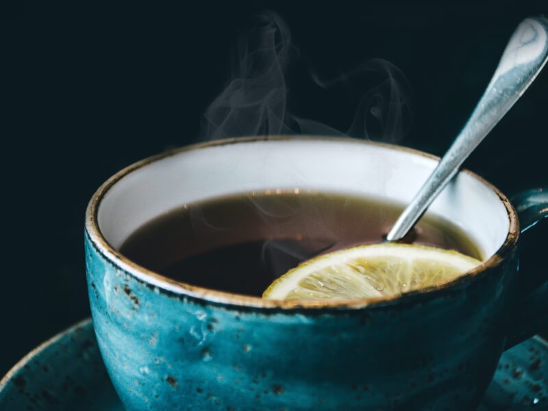 A cup of tea brewing with a lemon floating on top