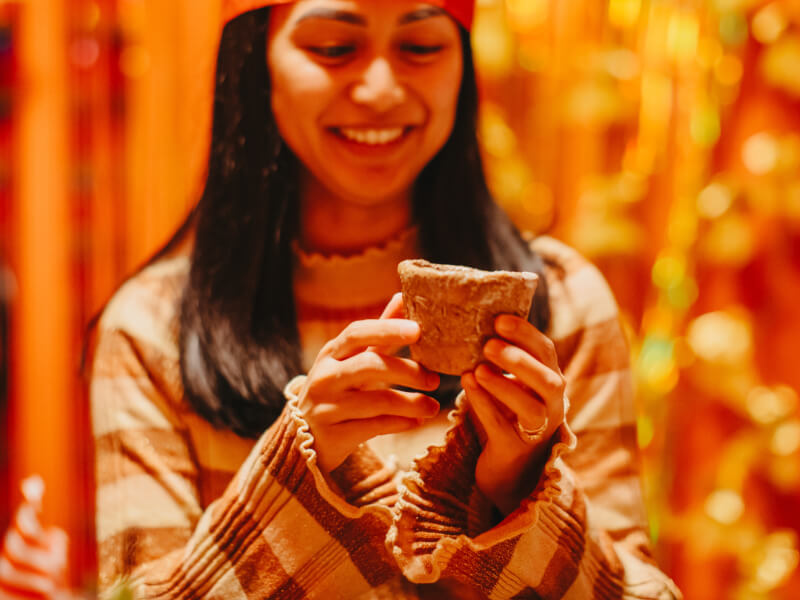 Woman smiling whilst holding a clay pot she made.