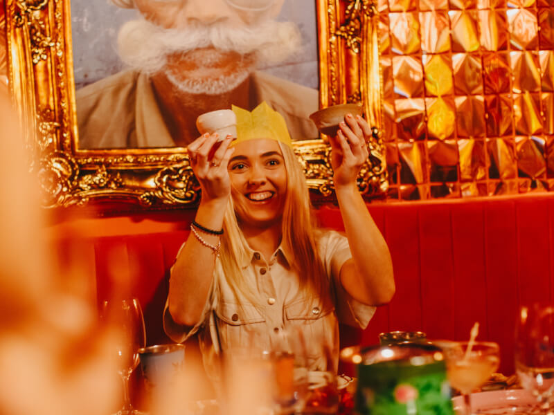 A woman smiling and holding up the ceramics she's made, surrounded by Christmas decorations