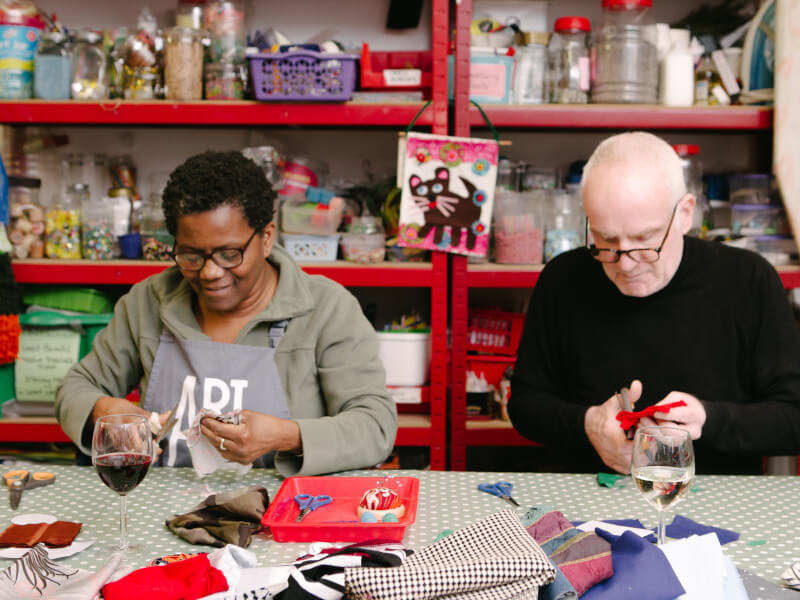 Two people work side by side at a sewing class