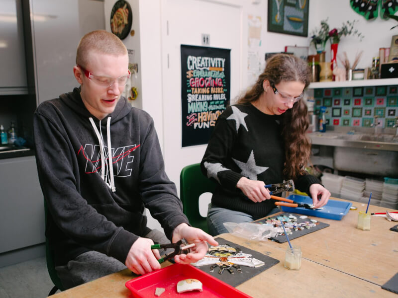 Two people working side by side at a mosaic class