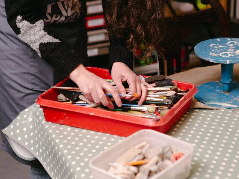 Hands rummaging in a box of paintbrushes