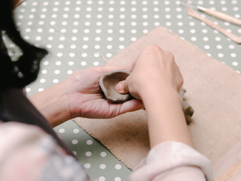 A close up of hands shaping a piece of clay