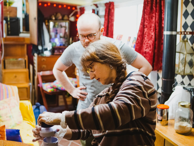 Two people are in a small kitchen on a houseboat, making churros