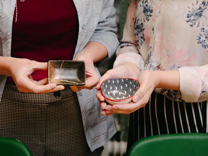 Two people holding up small kintsugi projects