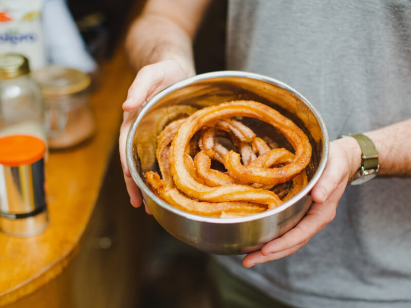 Someone holds a bowl full of handmade churros in a baking class.