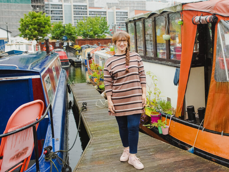 A smiling lady standing outside a moored houseboat