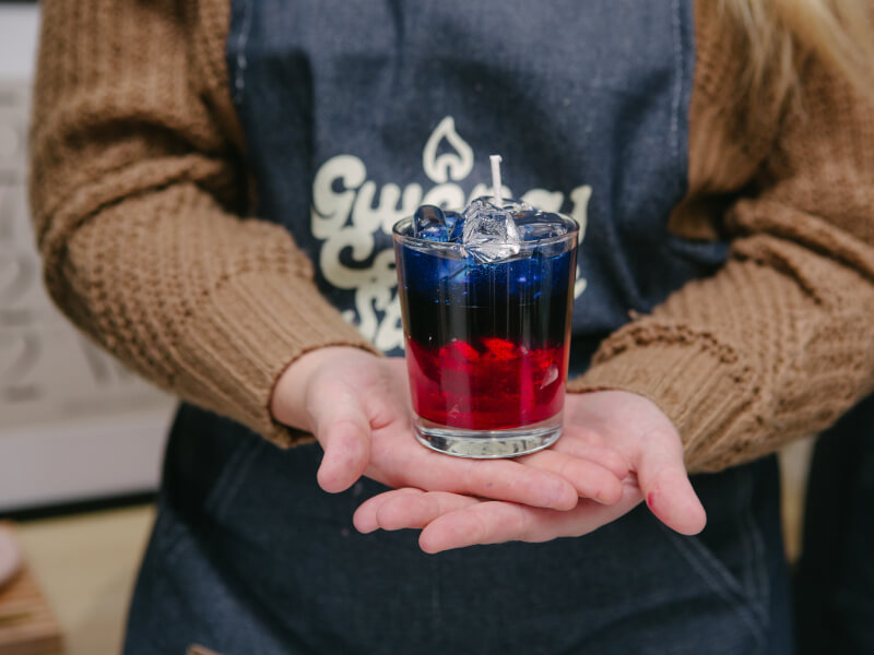 A person holding a blue and red gel candle