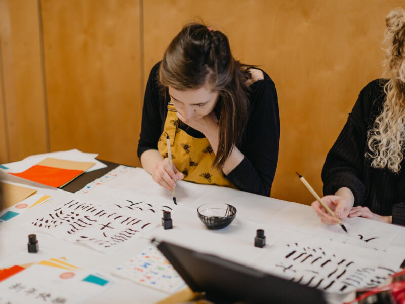 Person sitting at a table at a calligraphy class