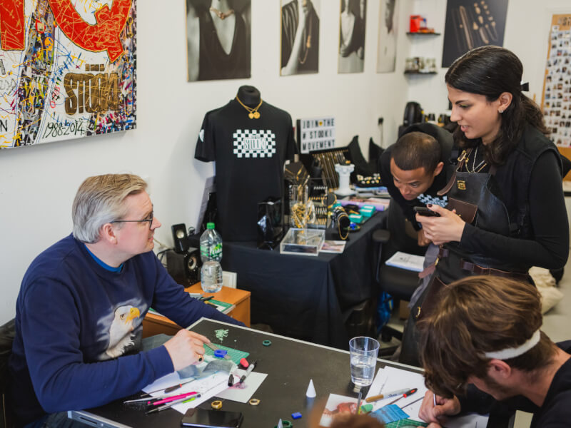 A teacher helps two students at a jewellery class