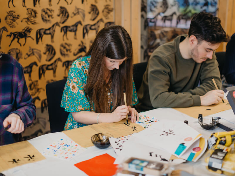 A group of friends sitting at a calligraphy class