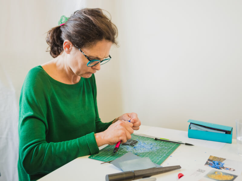 A woman in a green top is carving a wax mould at a jewellery making class
