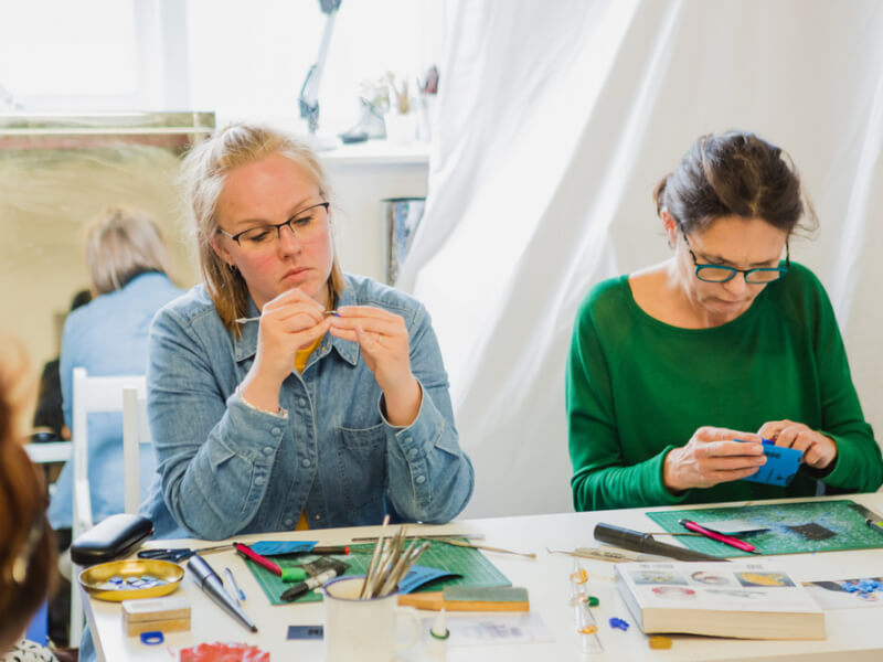 Two women sit side by side at a jewellery making class