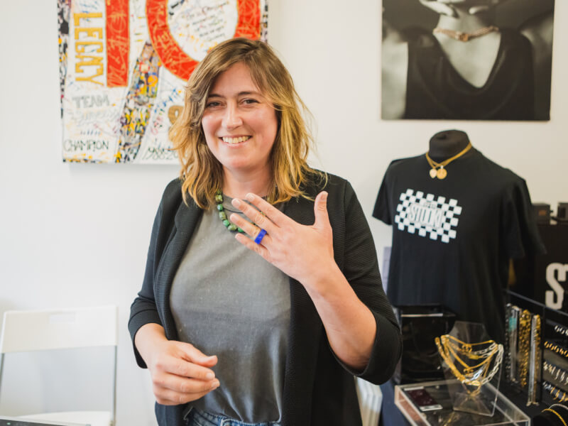 Woman smiling holding up a ring she made. 