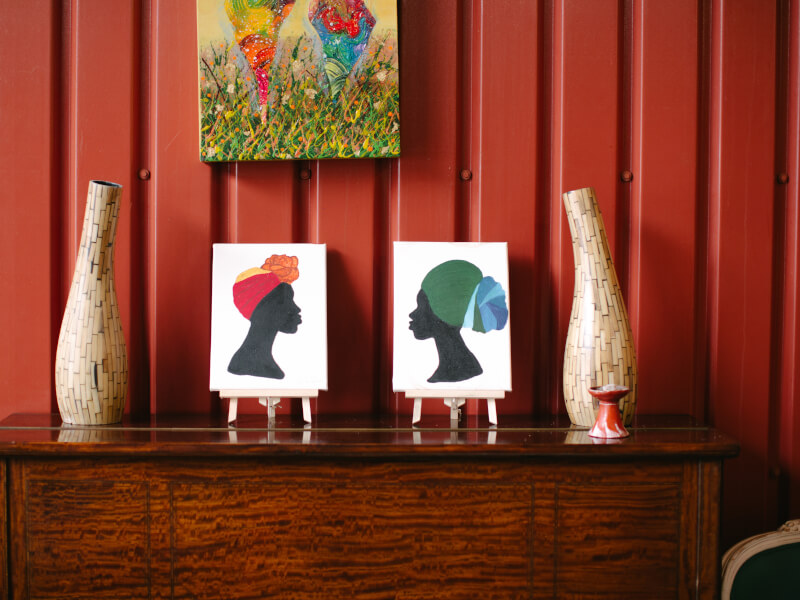 An interior shot of a red room two vases and painted silhouette portraits on a wooden sideboard