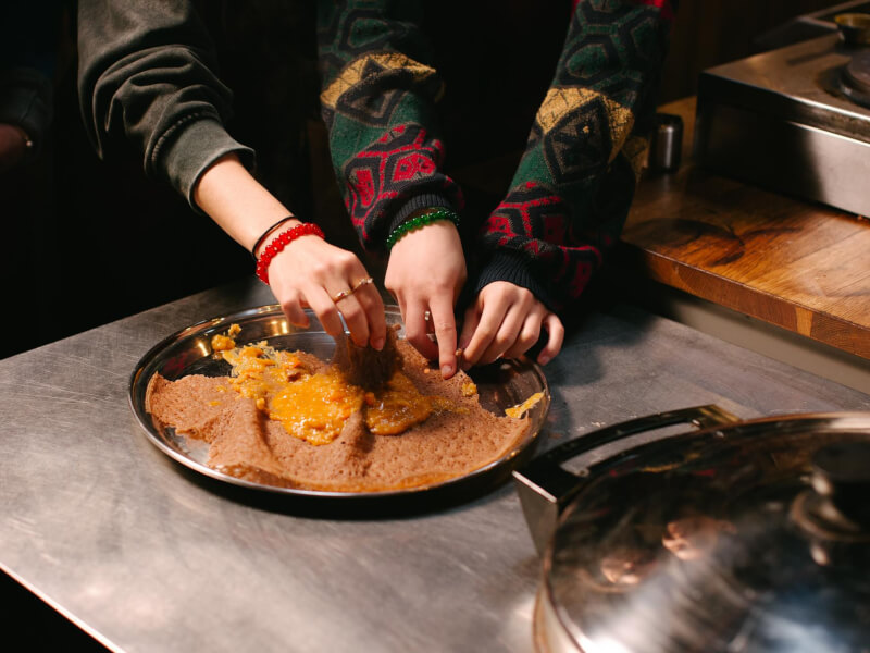 Hands reach around a platter of Ethiopian food