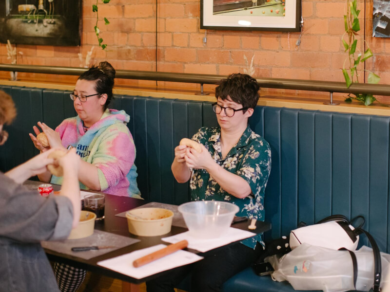 Two students sit side by side at a dumpling making class
