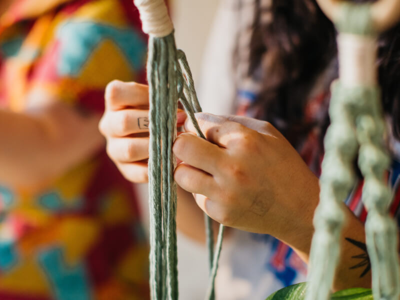 Close up shot of hands working with macrame cord.
