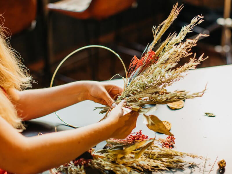 woman arranging a wreath from dried flowers