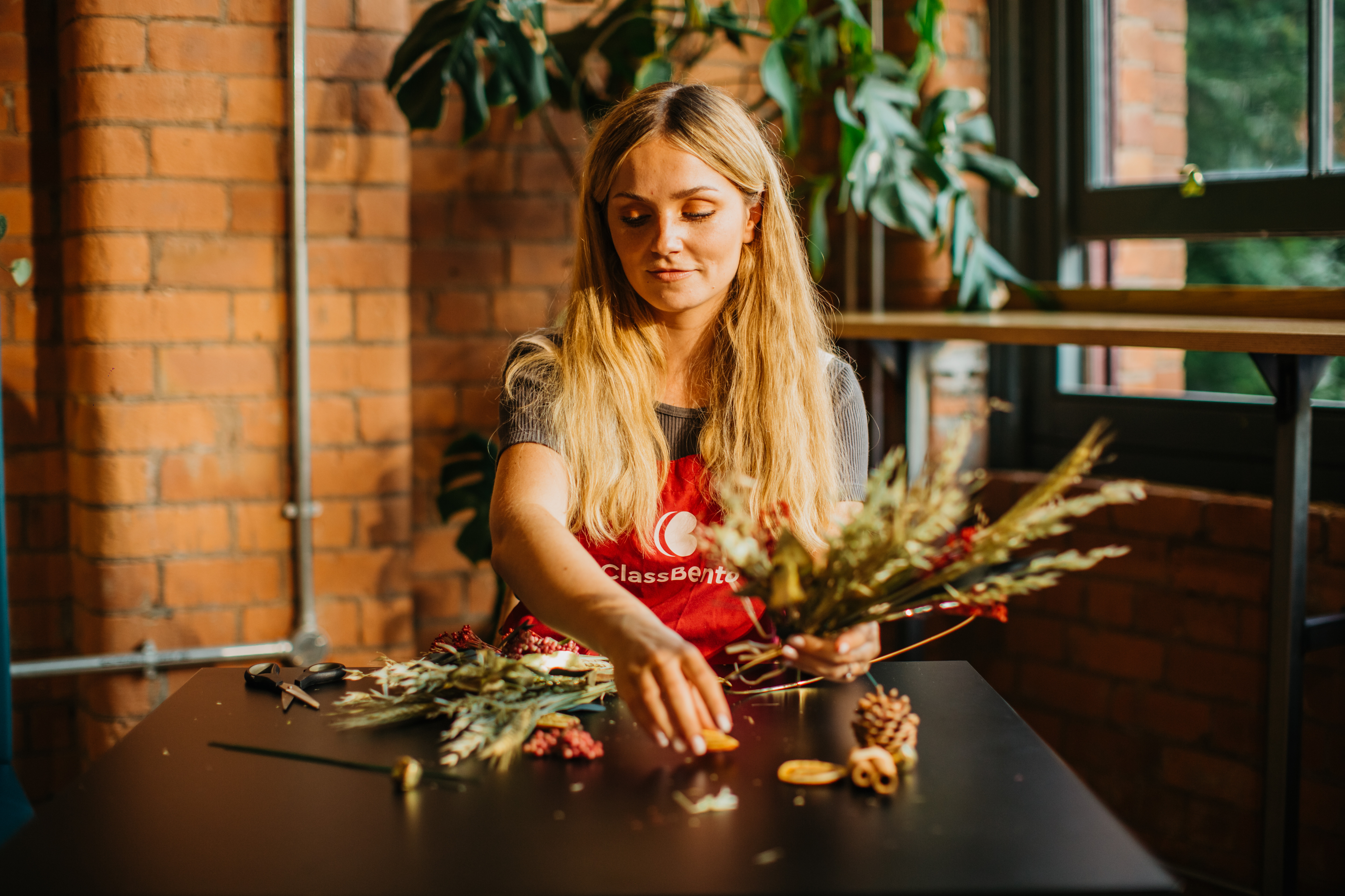A woman arranging dried flowers in a festive Christmas bouquet