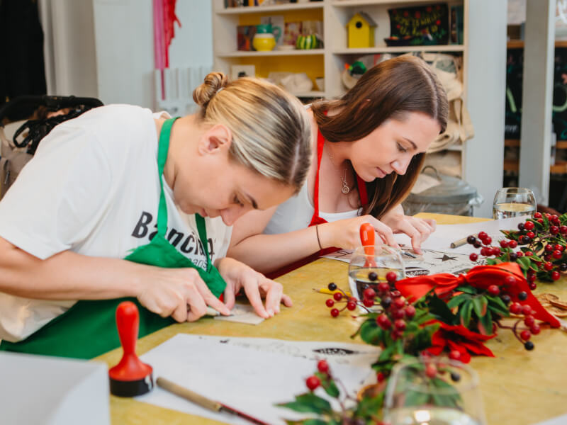 Two women are making linocut Christmas cards at a Christmas art class