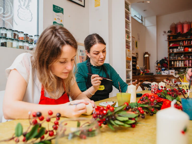 Two women working at a candle painting class