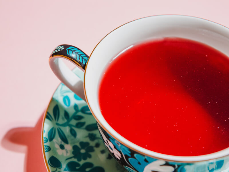 Close up of a floral cup filled with red tea on a matching saucer