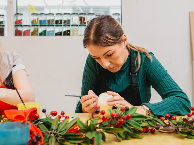 A woman concentrates as she paints at a candle painting class