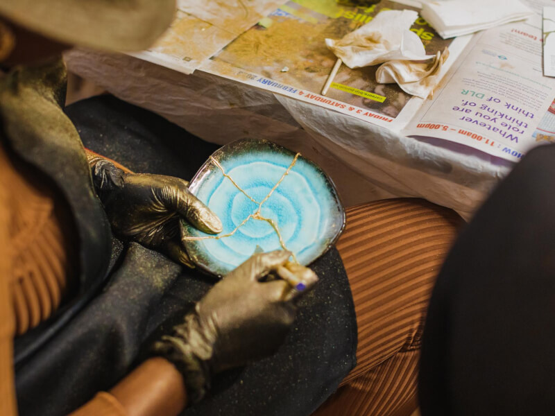 Close up of a person holding up a finished piece of kintsugi pottery