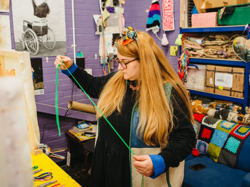 A student measuring yarn for a tufting project