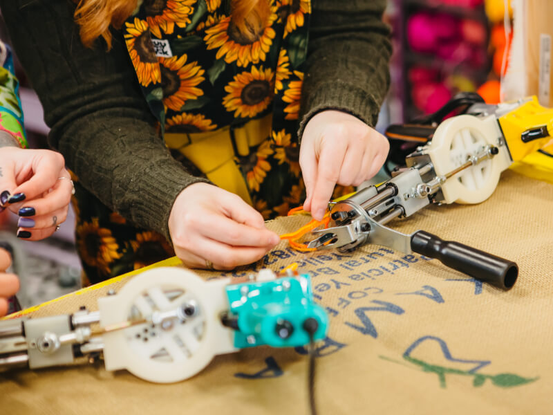 Close up of a person loading a tufting gun with yarn