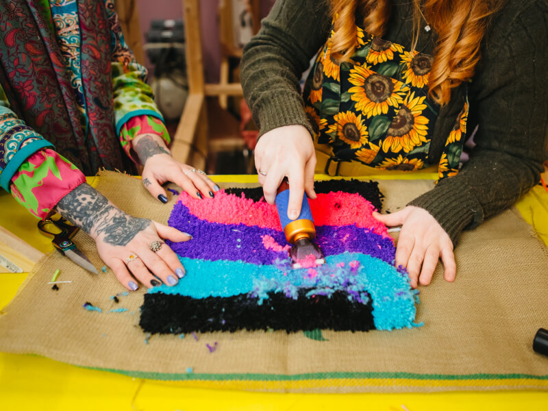 Close up of two people trimming a freshly tufted rug