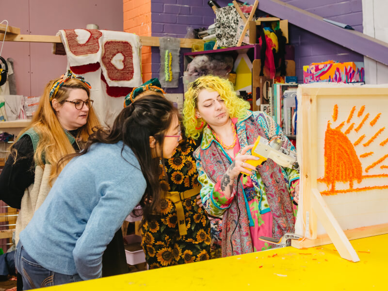 A group of women at a rug tufting class