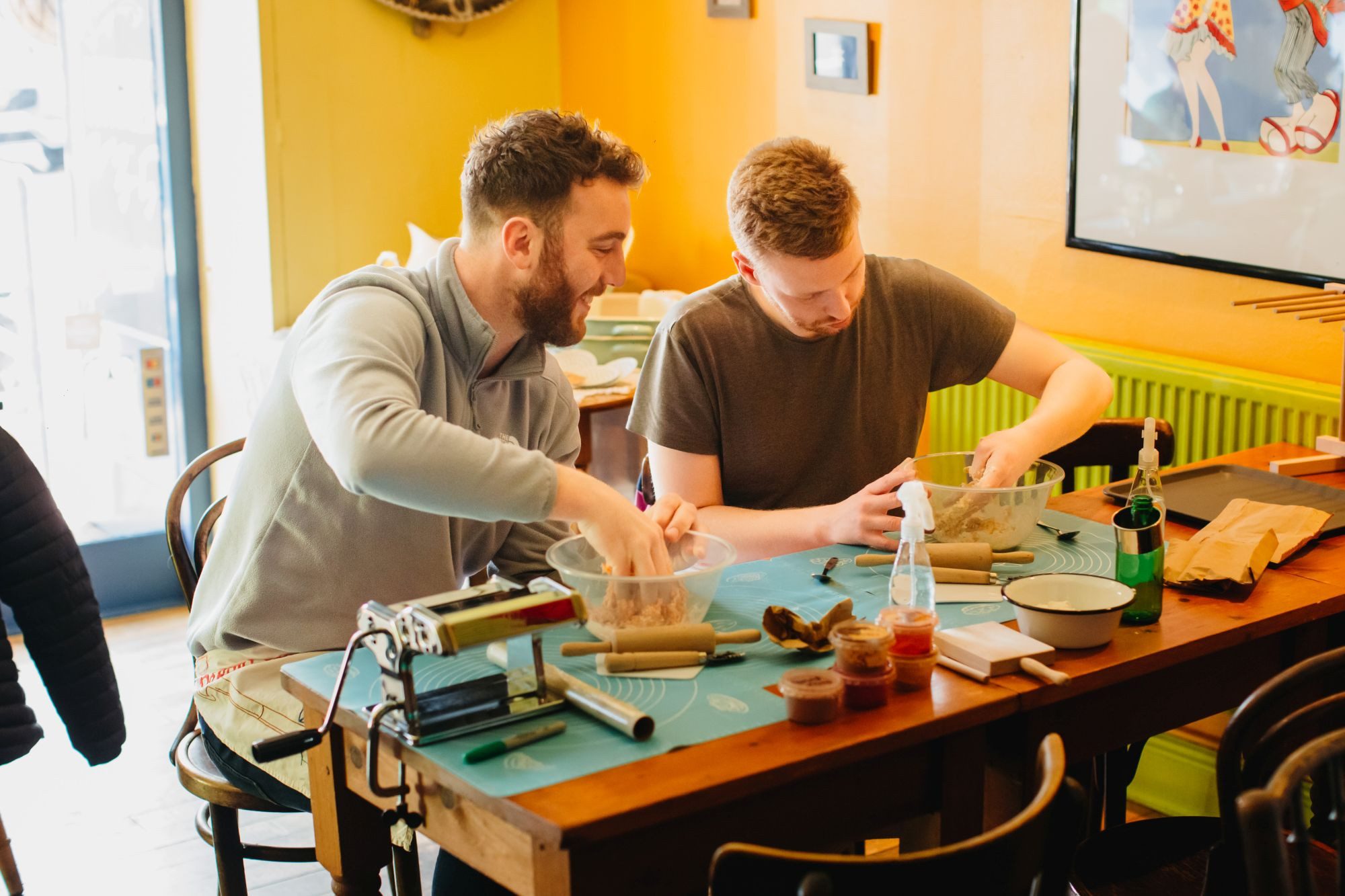 A couple smiling and laughing as they mix dough at a cooking class together