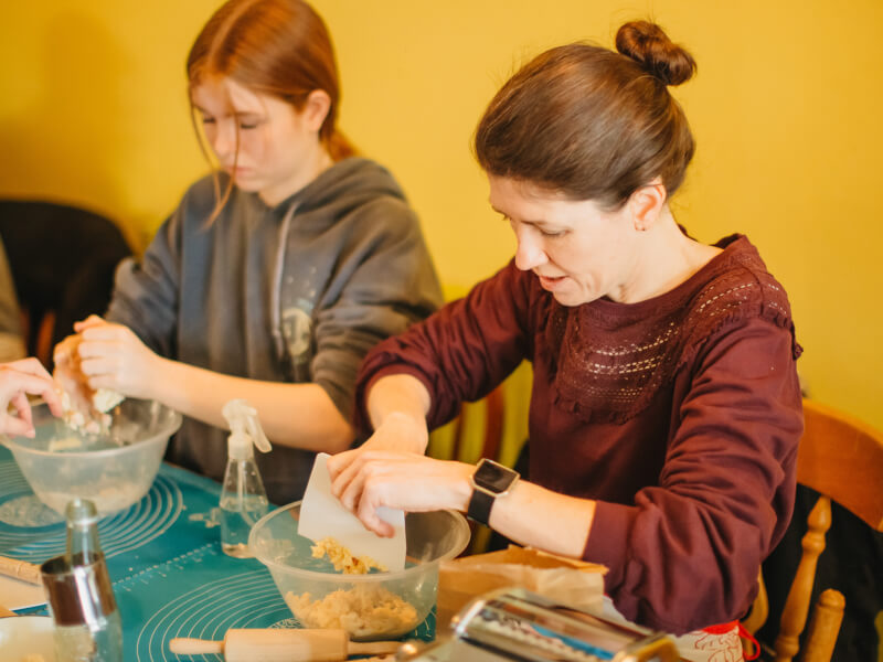 Two women at a pasta making class are mixing dough by hand in bowls