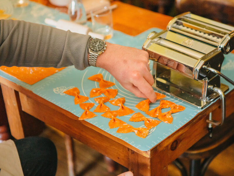Orange pasta shapes arranged in front of a pasta machine