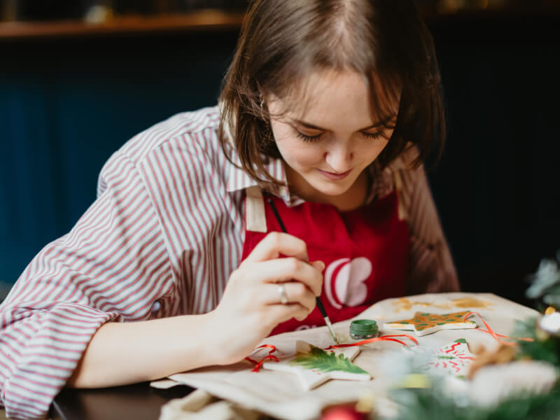 A person concentrating on painting a small ceramic star