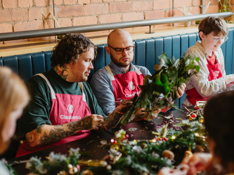 Two men wearing pink aprons at a floristry class